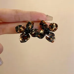Dettaglio orecchini a fiore in resina tartarugata retrò con eleganti centri neri lucidi