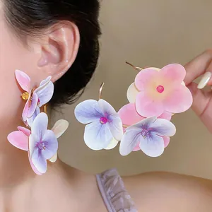 Detailed view of oversized fabric flower earrings in pink and purple gradient.