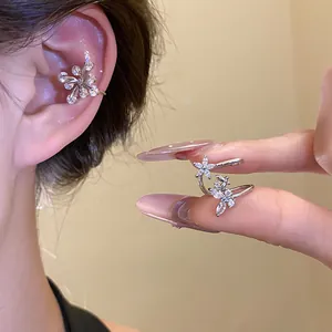 Close-up of sparkling zircon flower ear cuff on fingers showing delicate details