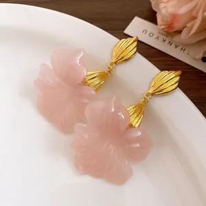 Detailed macro view of vintage pink resin flower drop earrings on a white plate