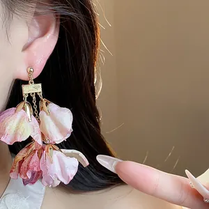 Detailaufnahme eleganter floraler Ohrringe mit zarten rosa Stoffblütenblättern am Ohr