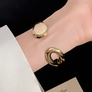 Macro view of an elegant gold water drop and oval open cuff bracelet on a female wrist