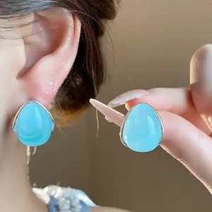 Primer plano detallado de pendientes de gota en acrílico azul con borde plateado fino