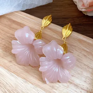 Macro view of pink resin flower earrings with vintage gold shell-shaped metal details