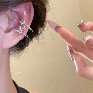 Detailed view of silver flower ear cuffs with sparkling zircons worn on a model's ear