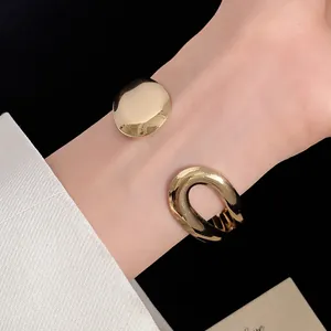 Detail of gold metallic open cuff bracelet with minimalist geometric ends on wrist