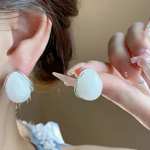 Primer plano de pendientes de gota de acrílico blanco minimalistas con poste de plata