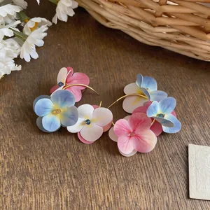 Close-up of colorful fabric flower hoop earrings on a rustic wooden table