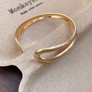 Detailed close-up of a gold metal open cuff bracelet with a vintage water-drop design.