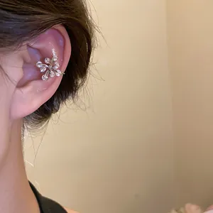 Close-up detail of silver zircon flower ear cuff on female model's ear cartilage