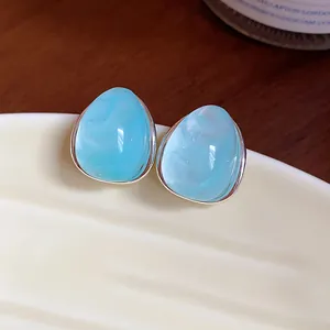 Primer plano de pendientes de acrílico azul claro con forma de gota y bordes plateados
