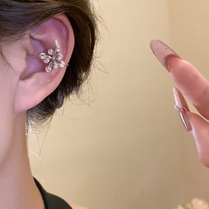 Detailed close-up of a stylish silver zircon flower ear cuff worn on the ear cartilage.