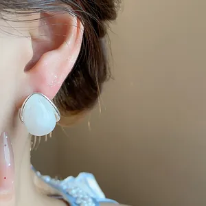 Primer plano elegante de pendientes de gota de acrílico blanco de estilo minimalista
