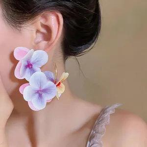 Detailed close-up of large purple fabric flower petal earrings for summer vacation style