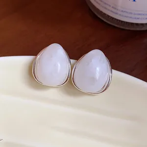 Vista macro de pendientes de gota en acrílico blanco minimalista con elegante acabado plateado