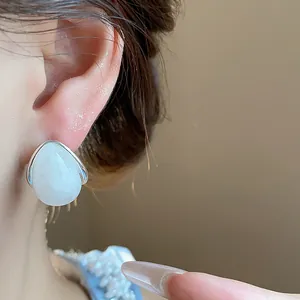 Detalle de cerca de un pendiente de gota de acrílico blanco usado en la oreja de un modelo