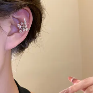 Close-up detail showing a shiny silver-toned zircon flower ear cuff worn on a female ear