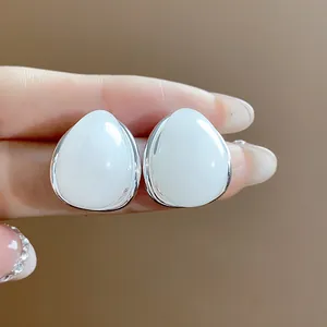 Primer plano de pendientes de gota de acrílico blanco minimalistas con pasadores de plata