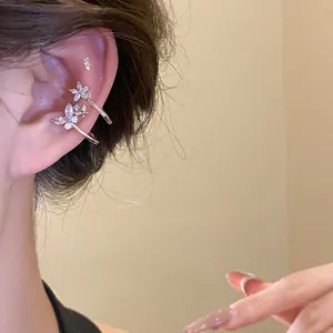 Detail shot of sparkling zircon flower and butterfly ear cuffs worn on ear.