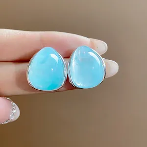 Primer plano de pendientes de gota de agua en acrílico azul claro con bordes plateados