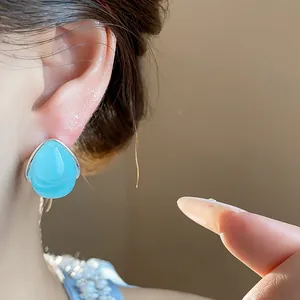 Primer plano de elegantes pendientes de gota de agua azul claro con base plateada para mujer