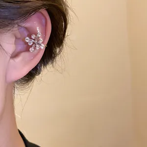 Detailed macro view of a sparkling silver flower ear cuff with zircons worn on ear