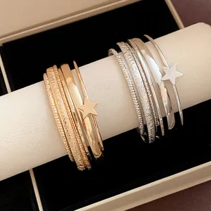 Primo piano di bracciali a stella multistrato in oro e argento su un espositore.