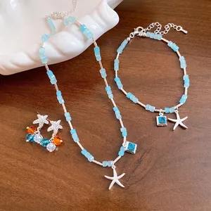 Parure de bijoux en perles bleu clair avec pendentifs étoile de mer, collier et bracelet.