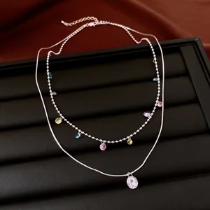 Detail view of vintage double-layered necklace with colorful zircons on black display.