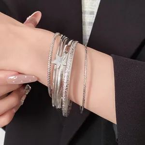 Dettaglio di un set di bracciali rigidi argentati con ciondolo a stella lucido