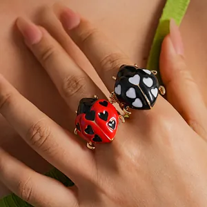 Vista dettagliata degli anelli in smalto a coccinella con motivi a cuore sulla mano