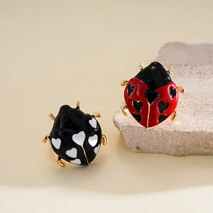 Vista dettagliata di anelli a forma di coccinella in smalto con cuori e finitura oro.