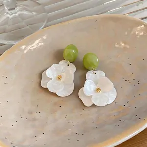 Resort style resin flower stud earrings featuring green beads and white pearlized petals