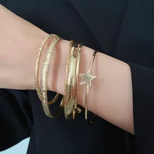 Dettaglio di un set di bracciali rigidi dorati a strati con ciondolo a stella