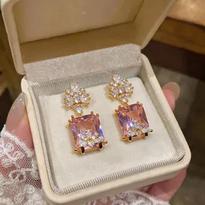 Eleganti orecchini rettangolari in zircone rosa mostrati in una scatola crema