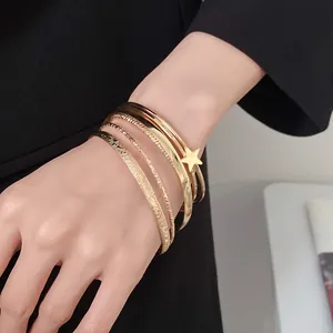 Elegante set di bracciali rigidi dorati con un raffinato ciondolo a stella al polso