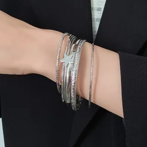 Dettaglio di set di bracciali rigidi multistrato in argento con ciondolo a stella