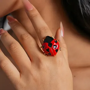 Primo piano di un anello a coccinella a forma di cuore in smalto rosso e nero con oro.