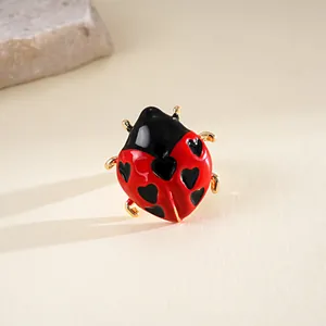 Primo piano di anello coccinella in smalto rosso con cuori e finitura in metallo dorato.