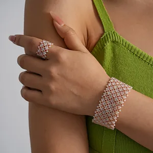 Detailed view of white and rose gold woven geometric seed bead bracelet and ring