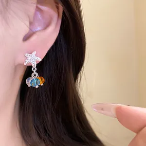 Détail d'une boucle d'oreille étoile de mer avec pampilles en cristal coloré