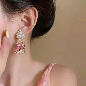 Eleganti orecchini a goccia in cristallo rosa quadrati indossati da una modella dettaglio