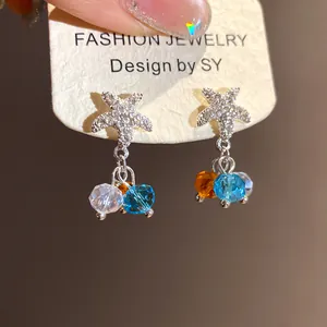 Gros plan de boucles d'oreilles étoile de mer avec perles colorées sur une carte