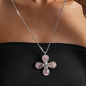Close-up detail of a pink resin four-leaf flower necklace worn by a model on black top.