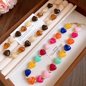 Collar de corazones de acrílico jaspeado de colores con cuentas doradas en joyero.