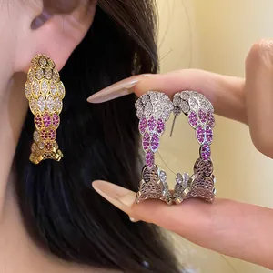 Close-up of pavé-set C-shaped hoop earrings featuring exquisite pink and white zircons