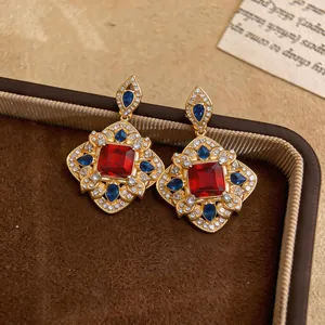 Gros plan détaillé de boucles d'oreilles vintage dorées avec pierres rouges et bleues