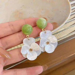 Detailed macro view of resin flower earrings with green marbled beads and gold accents