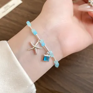 Gros plan d'un bracelet en perles bleu clair avec une étoile de mer et un pendentif