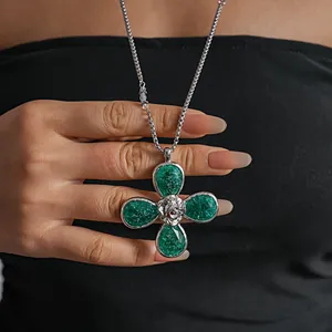 Close-up of a large green resin four-leaf flower pendant with textured ice-crack design.